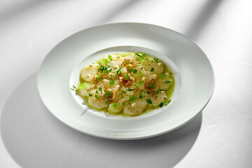 A close-up of scallop carpaccio, showcasing the tender texture of the scallops and the crispiness of the fresh herbs