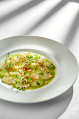 A close-up of scallop carpaccio, showcasing the tender texture of the scallops and the crispiness of the fresh herbs