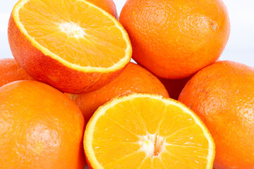 Several whole oranges and halved oranges arranged on a white background