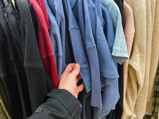 A person is currently holding a blue shirt in their hand, displaying an interest in fashion and clothing, perhaps considering styling it for an upcoming event or occasion