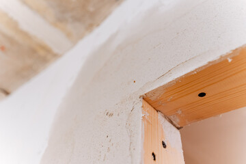 This is a closeup view capturing the details of a wooden beam juxtaposed against a smooth white wall, highlighting the beautiful contrast between the textures and colors