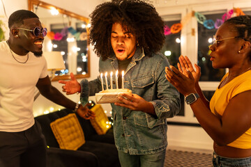 Man blowing birthday cake asking for wish next to friends