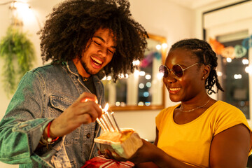 Friends lighting birthday cake's candles preparing a surprise at home