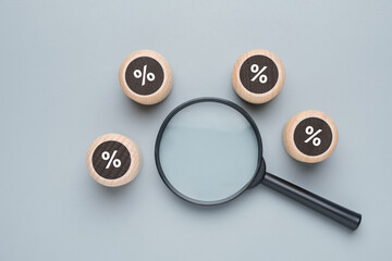 Percentage icon on the wood blocks around a magnifying glass, financial interest rate, business...