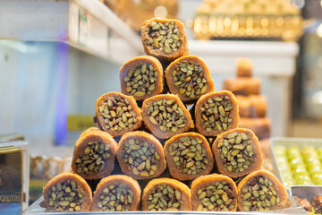 Close-up of traditional Turkish pistachio rolls, featuring a nut-packed filling wrapped in a sweet,...