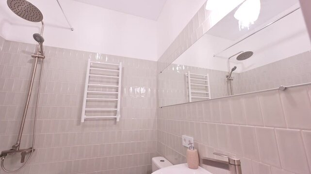 neutral-toned bathroom featuring a tub, shower, sink, toilet, heated towel rack, and large mirror