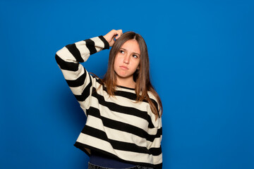 Hispanic teenage girl about 15 years old wearing a striped sweater and a puzzled facial expression,...