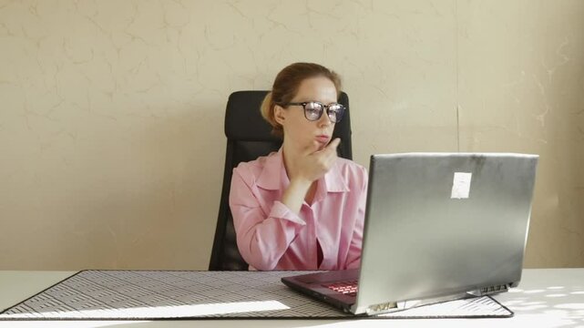Sad woman at laptop in office, professional navigating a career setback in a workspace, thinking about job challenges.