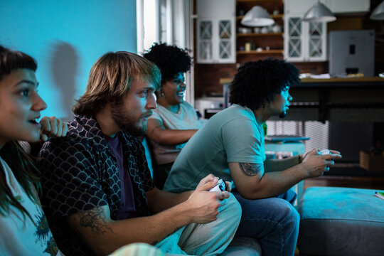 Group of friends playing video games with controllers at home