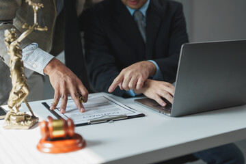 Two lawyers are discussing contract details, pointing at specific clauses on a clipboard, while...