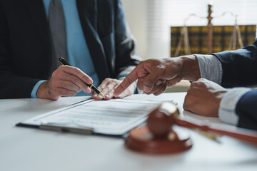Two lawyers are discussing contract details, pointing at specific clauses with a pen, with a gavel...