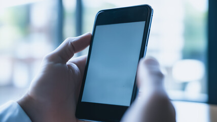 Smartphone Screen Mockup: A close-up shot of a hand holding a smartphone with a blank white screen, showcasing the device's modern design and sleek aesthetic.