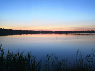 Scenic breathtaking tranquil pond at sunset with calm colorful sky reflection.