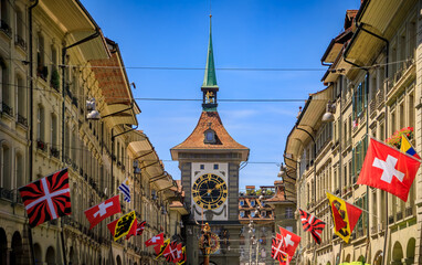 The Zytglogge clock tower with an ornate astronomical clock in the medieval Altstadt, Old City of Bern, Switzerland, flags on surrounding buildings