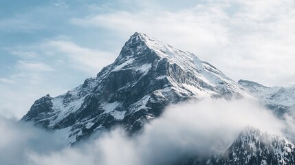 Obraz premium A majestic snow-capped mountain peak rises above the clouds in a serene winter landscape