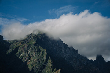 Towering mountains rise dramatically against the sky, partially obscured by rolling clouds. The scene captures nature's grandeur in a serene environment.