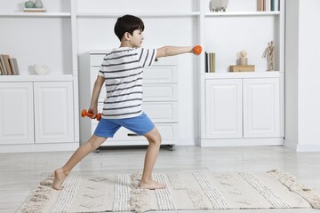 Little boy exercising with dumbbells at home. Morning routine