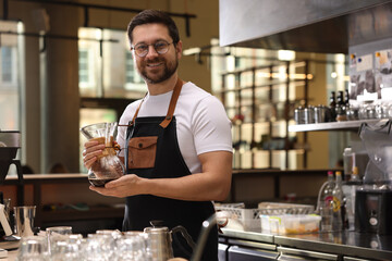 Fototapeta premium Barista with glass coffeemaker at table in cafe