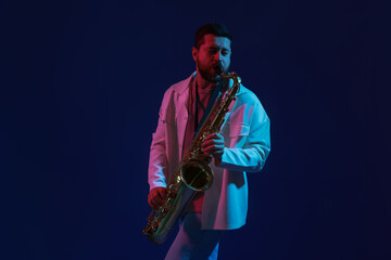 Professional musician playing saxophone on color background with neon lights