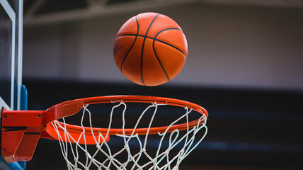 Fototapeta premium Basketball mid air, approaching vibrant red hoop, blurred indoor court