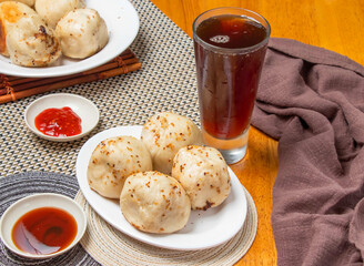 Pan Fried Buns 4 piece with Dipping Sauces and a tall glass of iced tea isolated on napkin side view of taiwan dim sum food