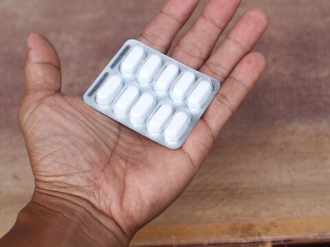 Paracetamol containing ten tablets in capsule form is in the palm of a person's hand