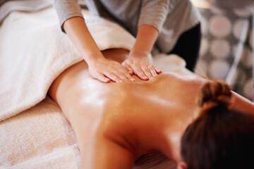 Woman, hands and masseuse with back massage at spa for beauty, physical therapy or body treatment at resort. Female person, lying and relaxation on bed at luxury salon for gentle rub or stress relief