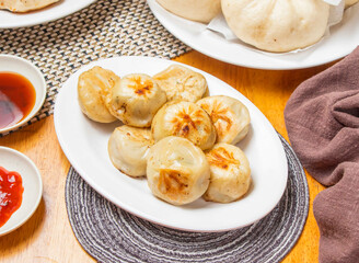 Shanghai Fried Buns 8 piece with Dipping Sauce served in plate isolated napkin side view of chinese dim sum food