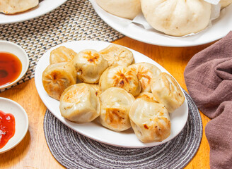 Shanghai Fried Buns or Momo with Dipping Sauce served in plate isolated napkin side view of chinese...