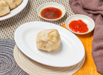 Shanghai Cabbage Buns or Steamed Momo with Dipping Sauce served in plate isolated napkin side view of chinese dim sum food