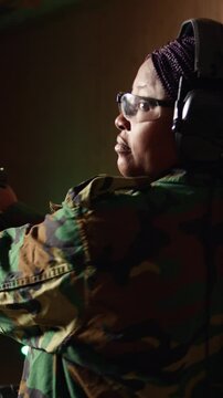 Vertical video Smiling woman in firing range doing recreational shooting activity with firearm, hitting bullseyes. Happy person in shooting gallery training with handgun, developing muscle memory