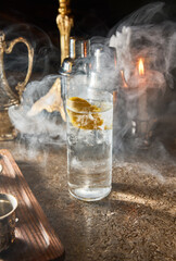 A glass of water with a slice of lemon in it sits on a table. The steam from the drink is rising, creating a hazy atmosphere