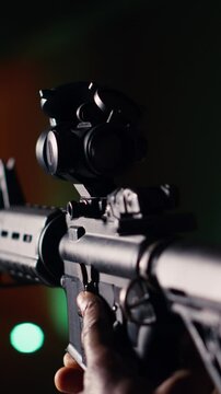Vertical video Man holds assault rifle, enjoying recreational shooting experience in firing range. Person practices with semiautomatic weapon in safe environment at shooting range company, camera B