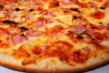 Pizza with ham and mushrooms on a white plate.