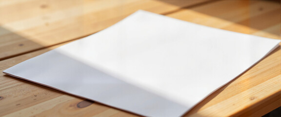 Blank flyer on wooden table, morning light creates soft shadows