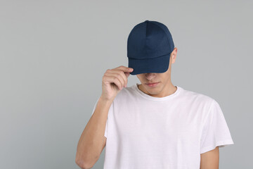 Man in stylish baseball cap on grey background. Mockup for design