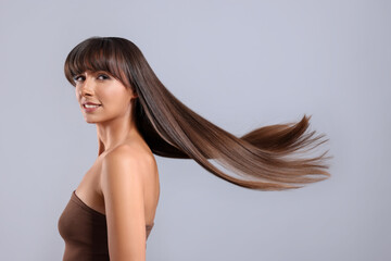 Hair styling. Portrait of beautiful woman with straight long hair on grey background, space for text