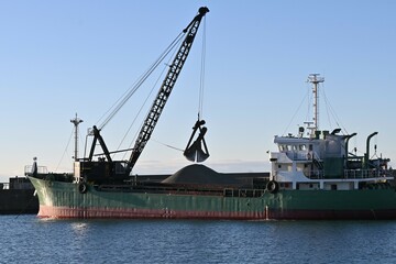 Obraz premium A scene of dredging work at the port. The purpose of dredging work is to scoop up sediment from the seabed with a dredger ship to ensure safe navigation of ships.