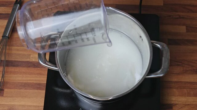 Preparing sugar syrup for cooking tangerine jam in a saucepan on the stove in a home kitchen