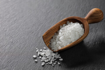 sea salt in scoop on black stone background
