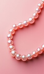 Obraz premium A delicate pink pearl necklace gracefully drapes against a soft pink background, highlighting its elegance and charm.