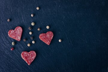 Salami in heart shape sliced on a cutting board, seen directly above. . Horizontal image with copy...