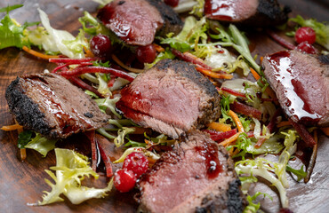 Grilled beef Striploin steak sliced on the grill and a close-up tomato. Clouse up