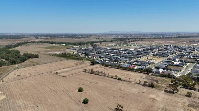 Aerial drone shot of new suburban development and undeveloped farmland in Tarneit, a rapidly growing suburb in Melbourne's west. New modern residential housing estates and ongoing transformation.