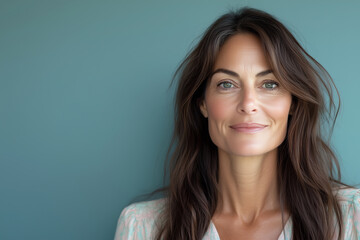 Naklejka premium Cheerful woman with long hair smiles at the camera in a pastel blouse against a neutral background