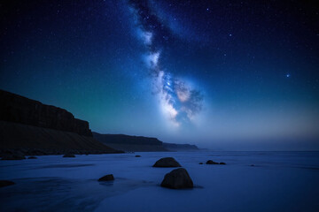 serene starry night sky over frozen rocky coastline with Milky Way