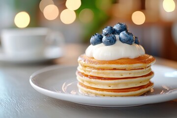 huge stack of pancakes topped with glazed blueberries 