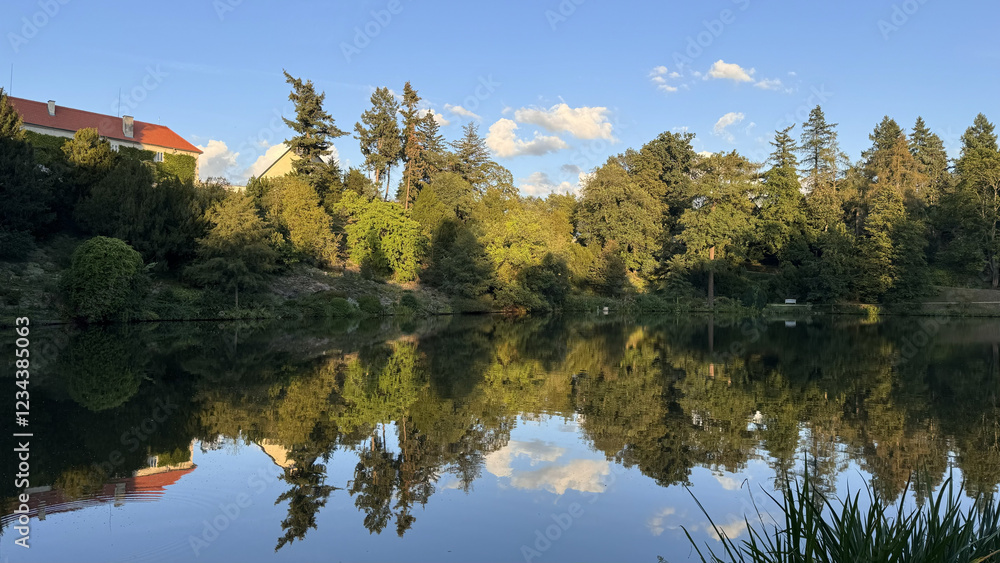 Poster lake with reflection of trees and building in the water. beautiful nature scenery with a calm lake r