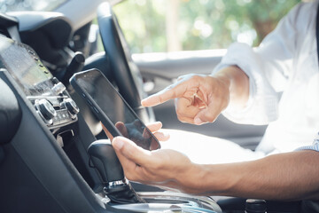 Naklejka premium Navigating the Road Ahead: A close-up shot of a hand using a smartphone for navigation while driving, capturing the modern reliance on technology for travel.