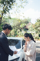 Car Accident Claim: A concerned woman reviews paperwork with an insurance adjuster following a car accident. The scene unfolds outdoors, near her damaged vehicle.